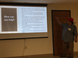 The President of the South Jersey Quail Project in front of a projector screen doing a presentation about Bobwhite quails.